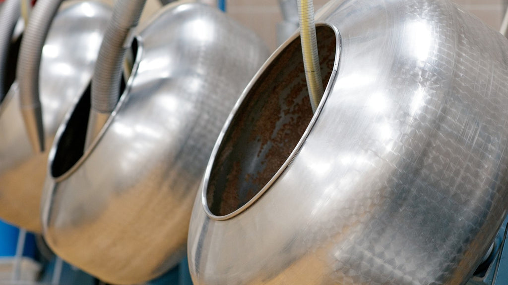 Shiny steel pans used for the chocolate panning process, showcasing the traditional tools of the art